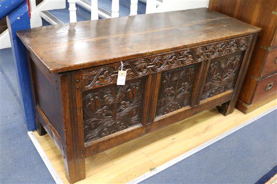 An 18th century oak coffer having planked top over three carved panels W.134cm